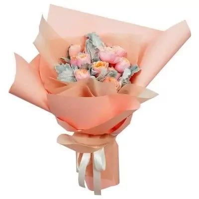 A bouquet of pink and orange roses with green leaves, wrapped in peach paper and tied with a white ribbon.