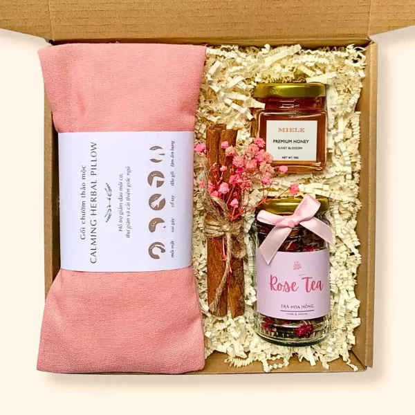 Gift box with pink herbal pillow, honey, rose tea, and cinnamon sticks.