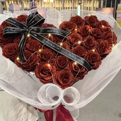 Heart-shaped bouquet of red glitter roses with fairy lights and black ribbon.