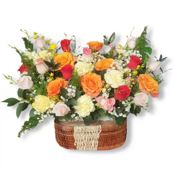 Basket of colorful roses, carnations, and filler flowers, with a woven basket.