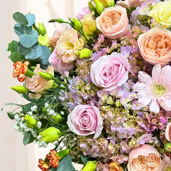 A bouquet of pink roses, peach roses, pink gerbera daisies, and other flowers.