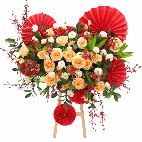 Floral arrangement with peach roses, white flowers, and red accents on a wooden stand.