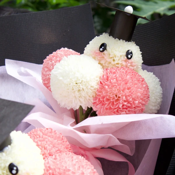 Floral arrangement of white and pink ping pong mums in a graduation theme.