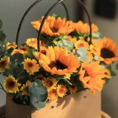 Basket of sunflowers and chrysanthemums with eucalyptus leaves.