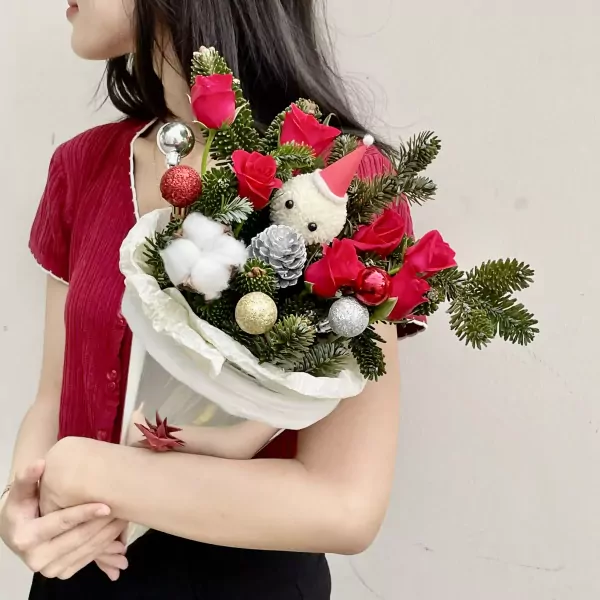 Christmas bouquet with red roses, pine branches, festive ornaments, and a cinnamon roll cone.