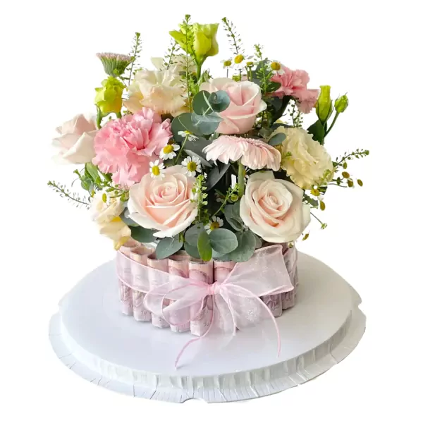 Floral money cake with pink roses, carnations, and daisies, adorned with a pink ribbon.