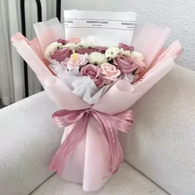 Subtle pink bouquet of roses and other flowers, wrapped in pink paper and tied with a ribbon.