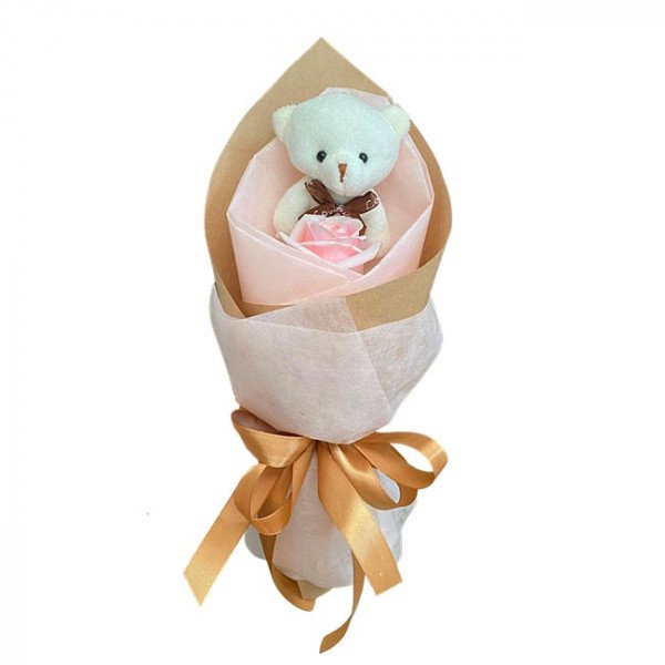 Small teddy bear and pink rose in bouquet with gold ribbon.
