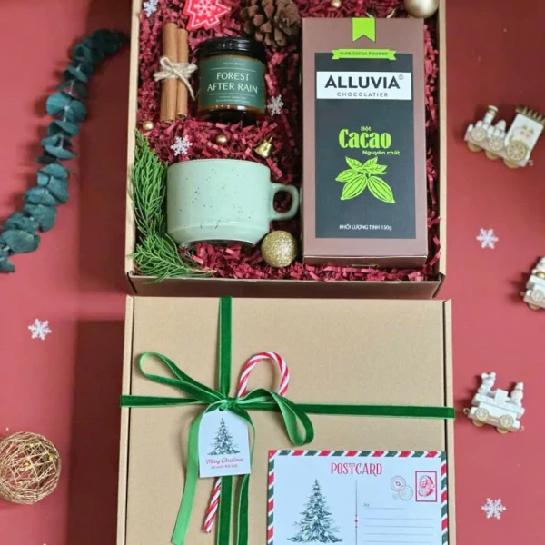 Christmas gift box with cocoa powder, mug, candle, cinnamon sticks, and festive decorations.