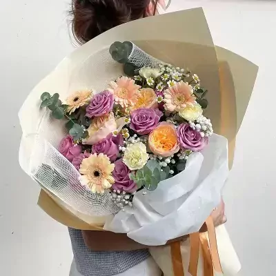 Bouquet with purple roses, orange David Austin roses, yellow gerberas, and white carnations.