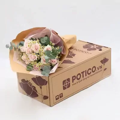 A pink rose bouquet and eucalyptus arranged on a cardboard flower box.