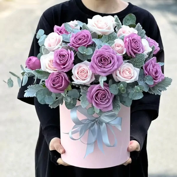 Pink box with purple and pink roses and green leaves, tied with a gray ribbon.