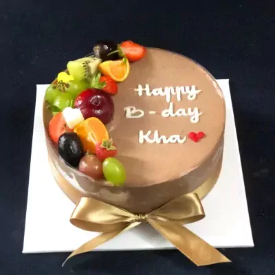 Chocolate mousse cake with fresh fruits and "Happy B-day Kha" written in white icing.