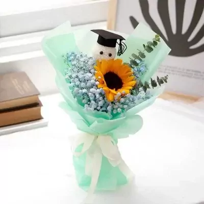 Sunflower bouquet with baby's breath and a graduation cap-wearing teddy bear.