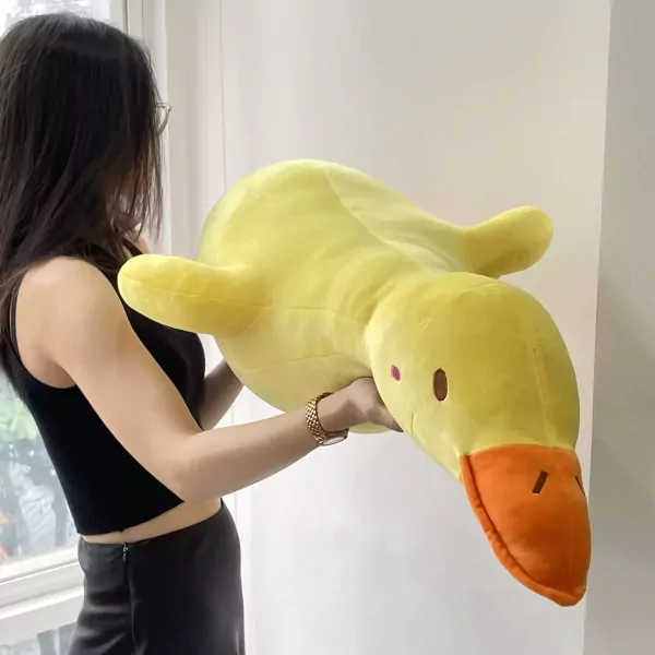 Giant yellow duck plush toy held by a woman wearing a black tank top and skirt.