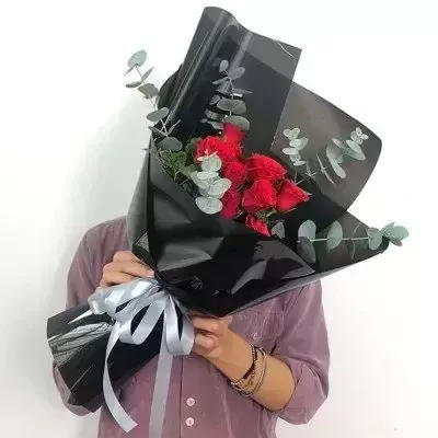Bouquet of red roses wrapped in black paper with silver ribbon.