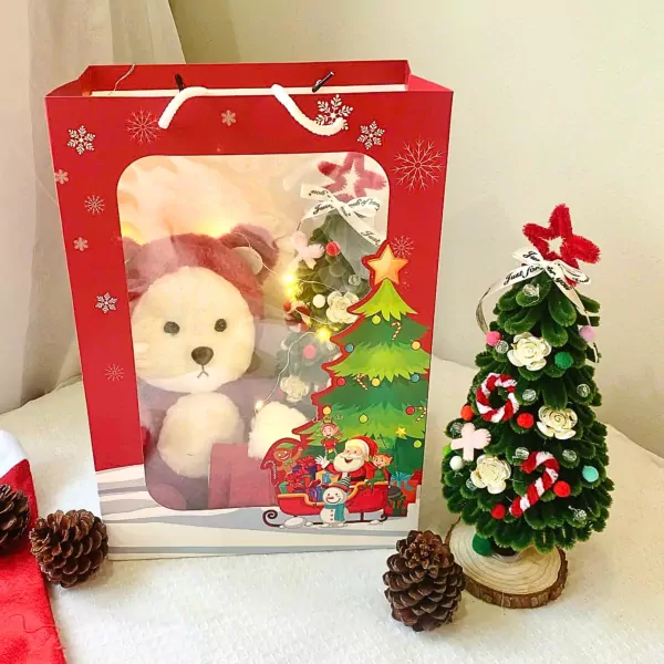 Christmas gift bag with teddy bear, tree, Santa, and pinecones.