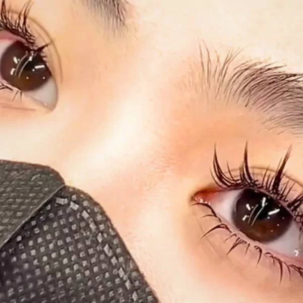 Close-up of a person's eyes with long, dark eyelash extensions and a black mask.
