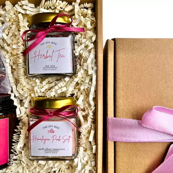 Gift set with two glass jars of tea and pink salt, a cardboard box, and pink ribbon.
