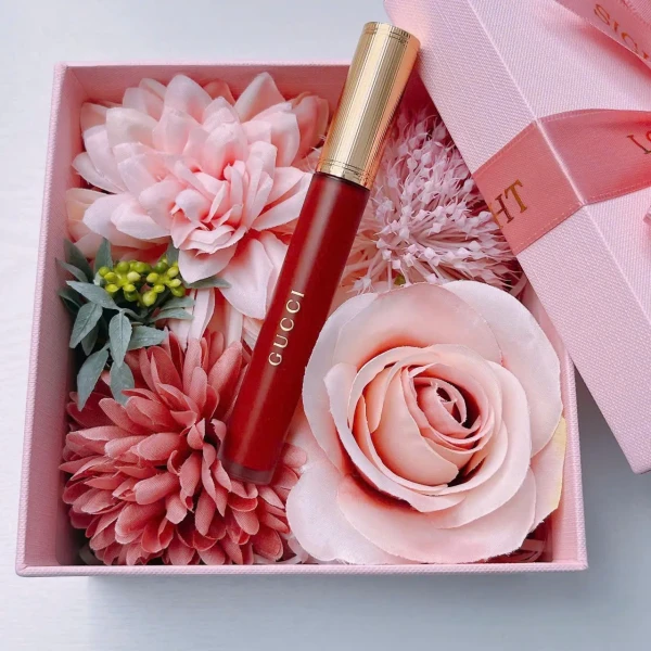 Gucci lipstick in a gift box with pink flowers and a pink ribbon.