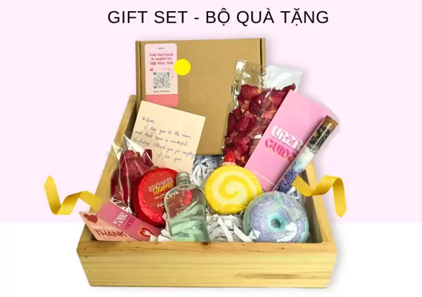 Gift box with bath bomb, soap, body oil, rose petals, and note.