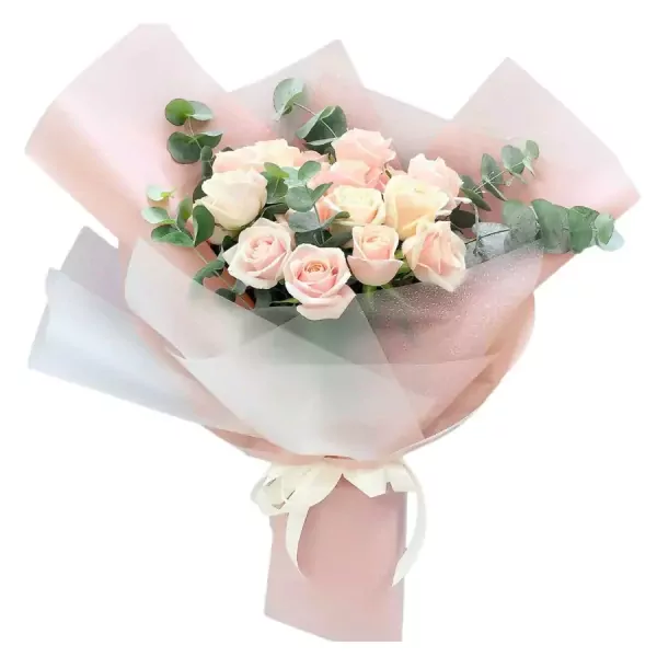 Bouquet of pink and cream roses with eucalyptus leaves in pink and white paper wrap.