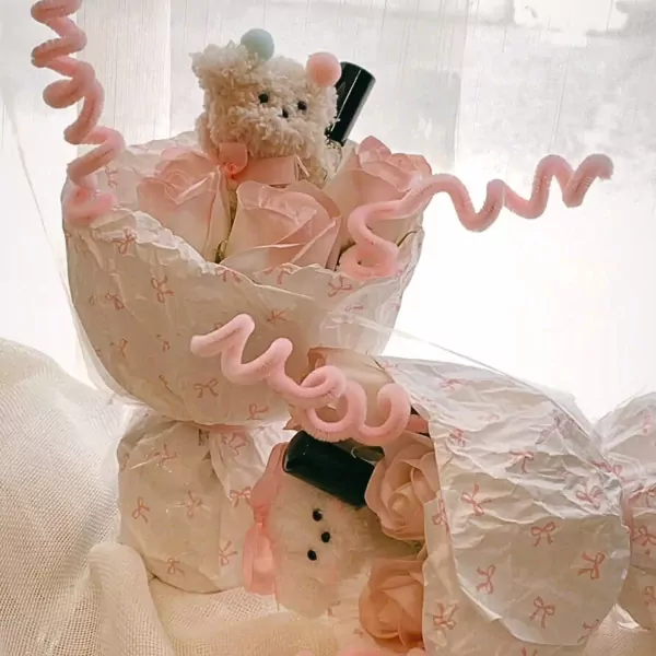 Plush teddy bears and pink paper roses in a decorative bouquet with piped pink trim.