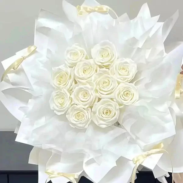 A bouquet of white roses wrapped in white paper with yellow ribbon accents.