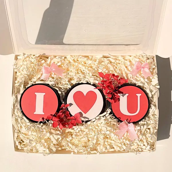 Gift box with 'I', heart, and 'U' shaped candles, decorated with pink bows and red flowers.