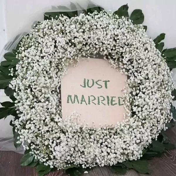Wedding car wreath with white baby's breath flowers and "Just Married" sign.