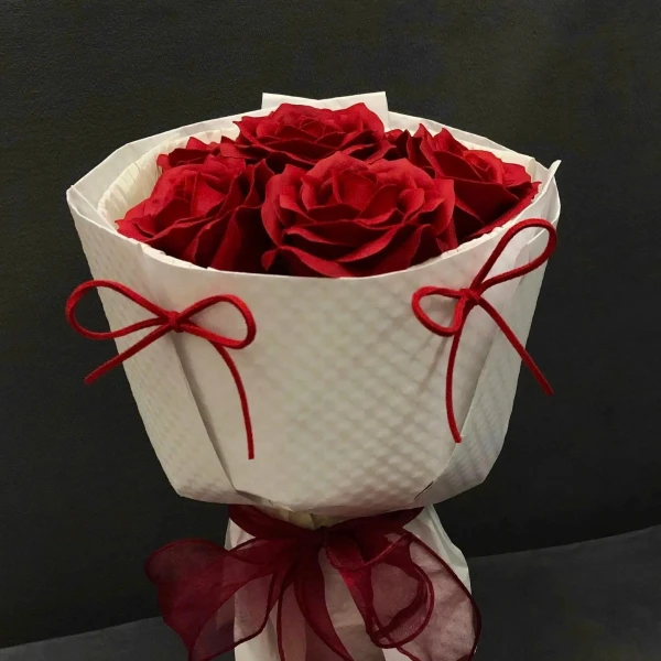 Red soap roses in a white bouquet with red ribbon ties.