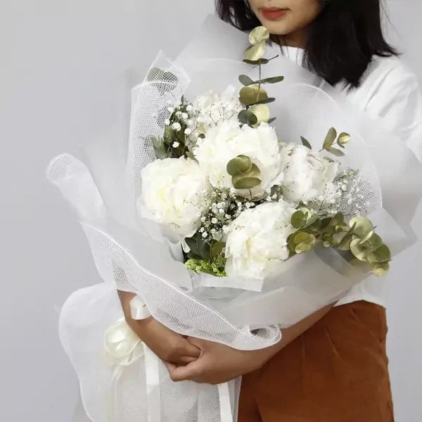 White peony bouquet with eucalyptus and baby's breath, wrapped in white mesh.