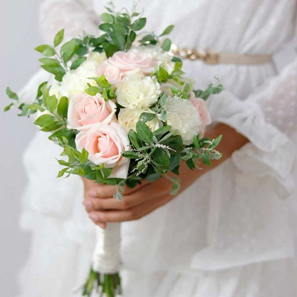 Bridal bouquet of pink and white roses and white carnations with greenery.