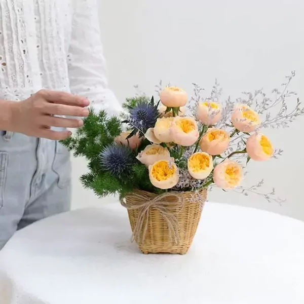 Wicker basket with peach roses, thistle, and greenery.