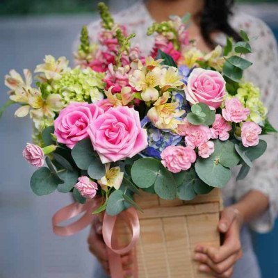 Wooden box of pink roses, hydrangea, carnations, and snapdragons.