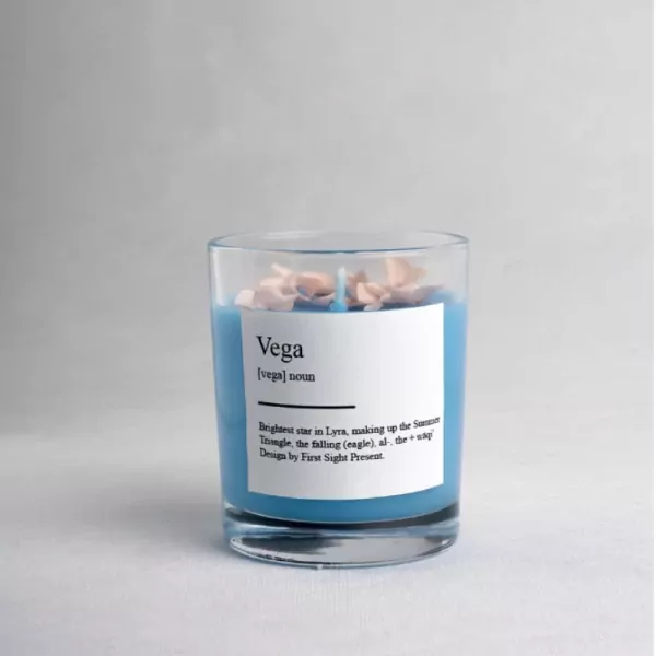 Blue scented candle in a glass jar with a label defining "Vega."
