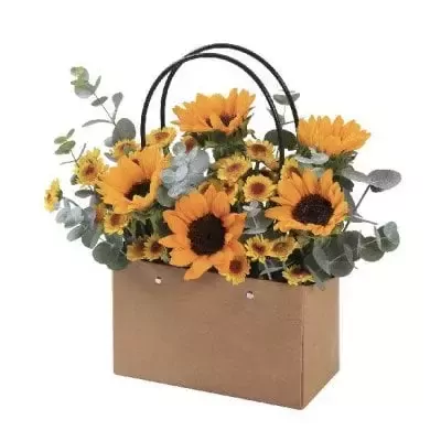 Brown paper bag filled with sunflowers and yellow daisies, accented with eucalyptus leaves.