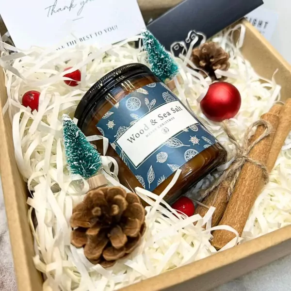 Christmas gift box with candle, pinecones, cinnamon sticks, mini trees, and ornaments.