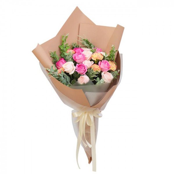 Bouquet of pink and white roses and carnations in brown wrapping with a cream ribbon.